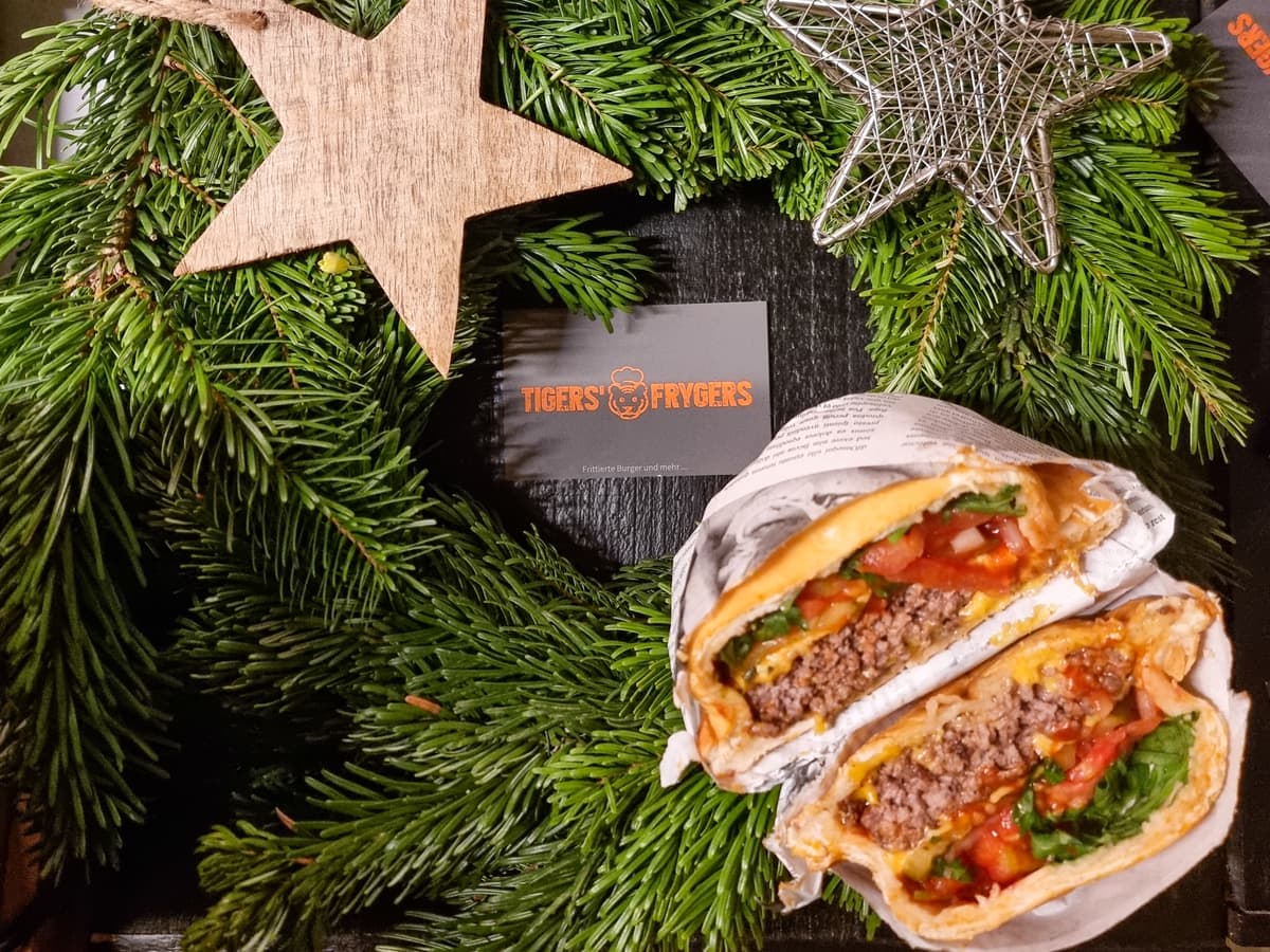 Aufgeschnittener Fryger auf Tannenzweigen, daneben ein Holzstern und eine Karte von Tigers' Frygers